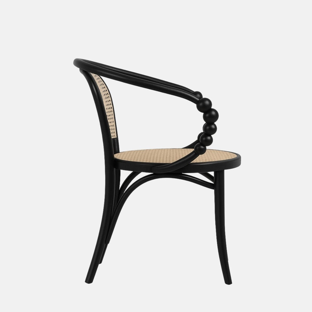 Contemporary armchair with a black wooden frame, curved beaded armrests, and woven cane seat and backrest in natural rattan.