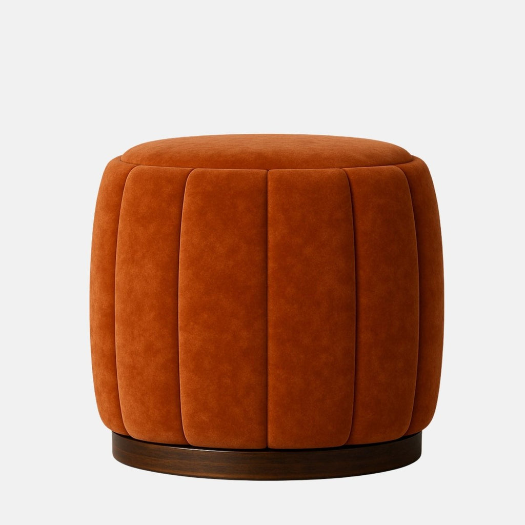 Rust velvet round ottoman with vertical panel upholstery and dark wood base modern upholstered stool or footrest for living room, bedroom, or hotel lounge.