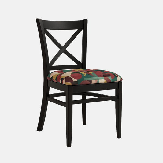 A black wooden dining chair with an X-shaped backrest and straight tapered legs. The seat is upholstered in a bold geometric fabric with red, green, gold, and beige shapes, creating a striking contrast against the matte black frame. Photographed on a light background with realistic shadows.