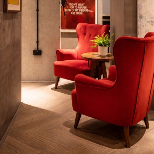Luxury red velvet accent armchairs with wooden legs in modern lounge seating area