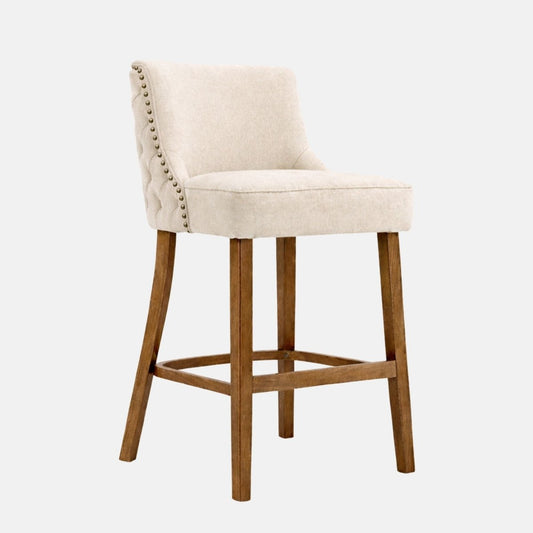 Cream upholstered regency bar stool with button tufted back, studded trim and solid wooden frame