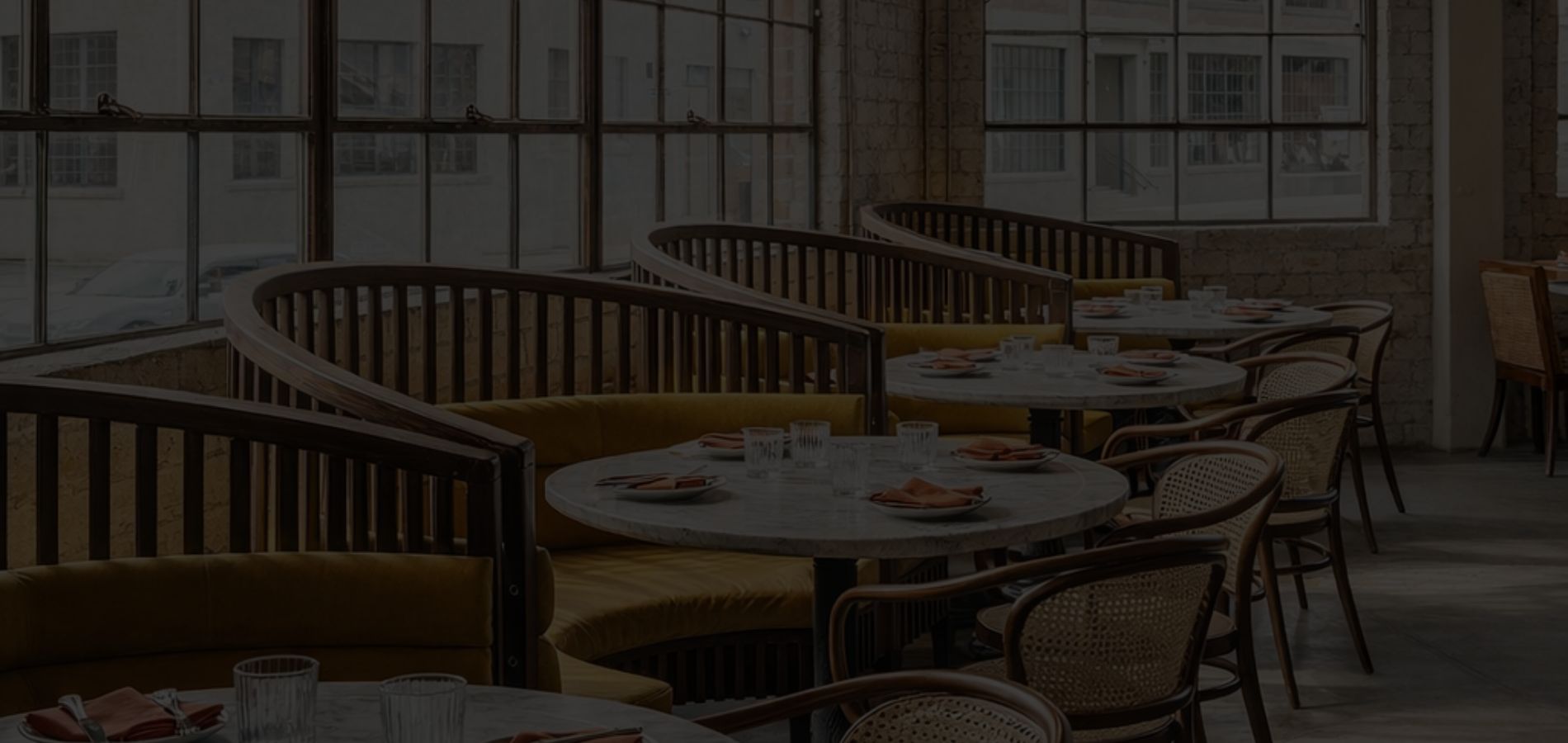 Restaurant interior with curved upholstered banquette booth seating and round dining tables