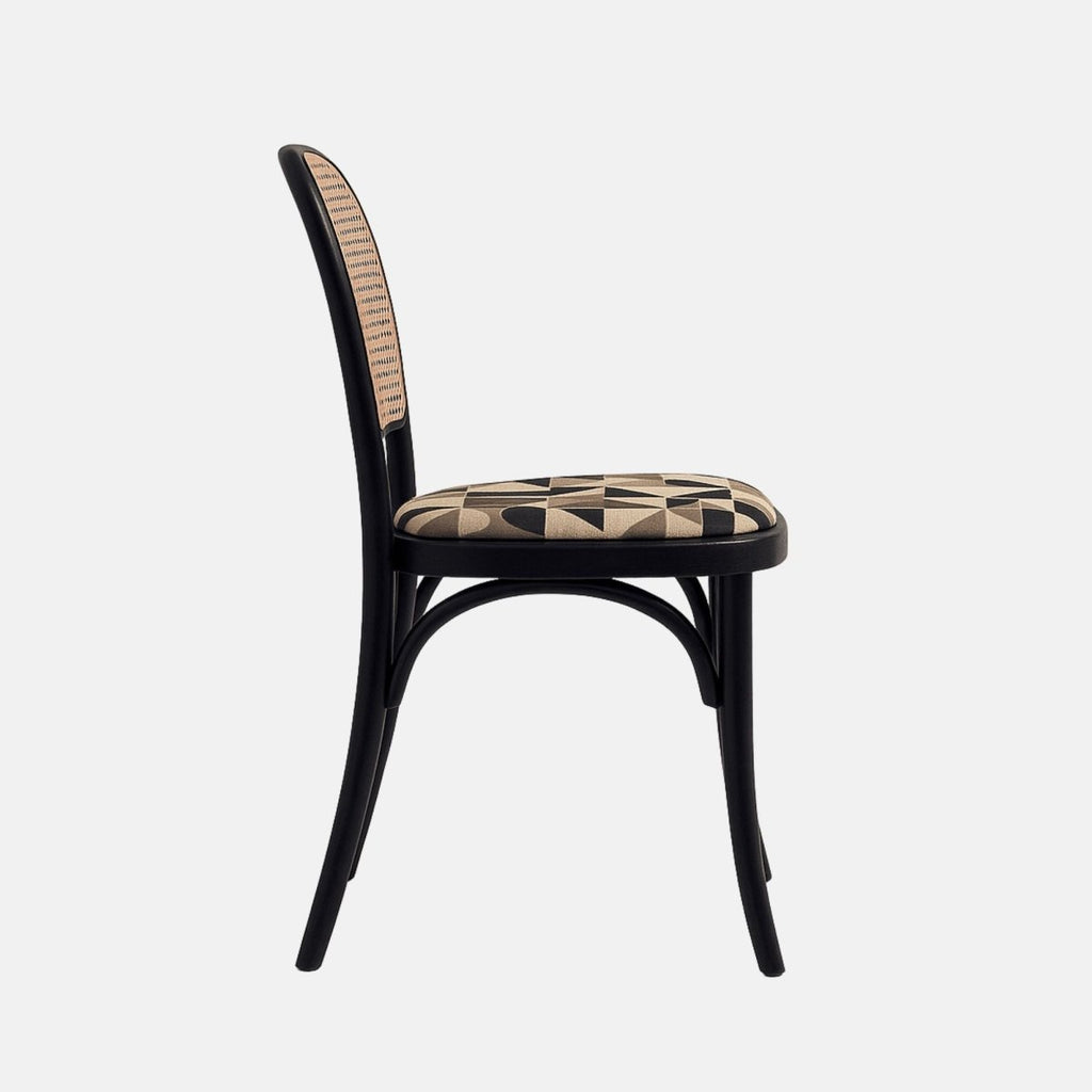 A black bentwood dining chair with a natural cane backrest and a cushioned seat upholstered in a beige and black geometric patterned fabric, shown from a straight side angle against a neutral background.
