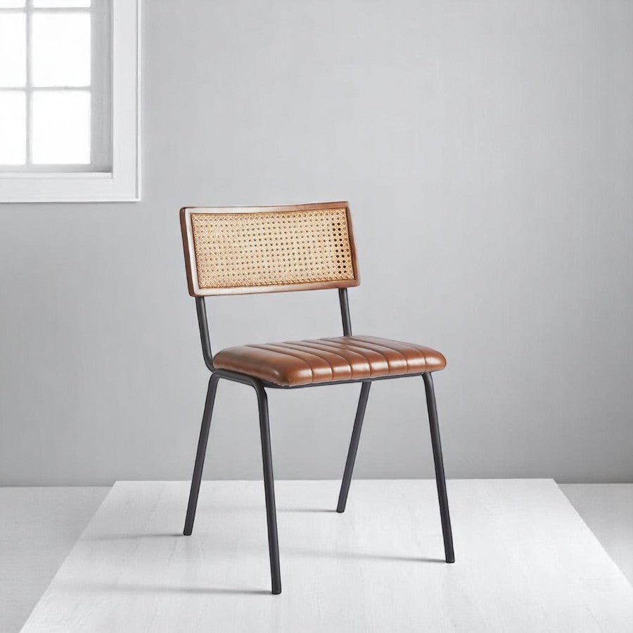 alt="Contemporary dining chair with rattan back and line-stitched leather seat on a metal frame"