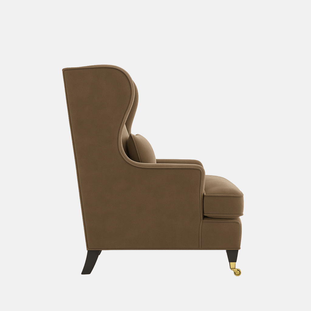 Brown upholstered wingback armchair with a matching lumbar cushion, rounded arms, and dark wooden legs with brass front castors