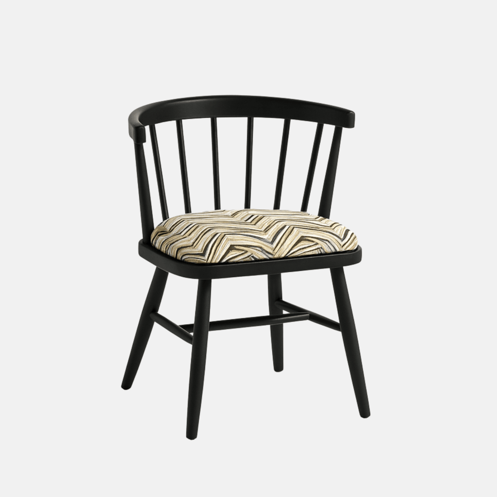 A modern black Windsor-style chair with a curved spindle backrest and four angled legs, featuring a cushioned seat upholstered in a geometric zigzag fabric with neutral tones. The chair is photographed against a light beige background with soft shadows for a clean, realistic presentation.
