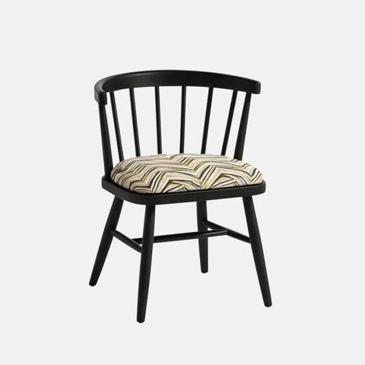 A modern black Windsor-style chair with a curved spindle backrest and four angled legs, featuring a cushioned seat upholstered in a geometric zigzag fabric with neutral tones. The chair is photographed against a light beige background with soft shadows for a clean, realistic presentation.
