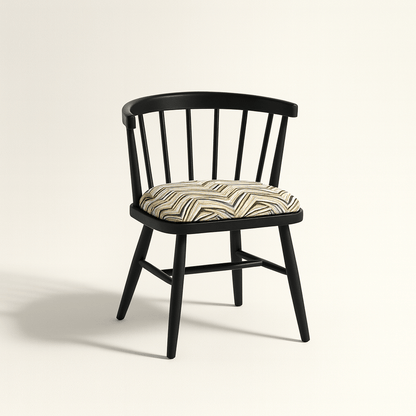 A modern black Windsor-style chair with a curved spindle backrest and four angled legs, featuring a cushioned seat upholstered in a geometric zigzag fabric with neutral tones. The chair is photographed against a light beige background with soft shadows for a clean, realistic presentation.