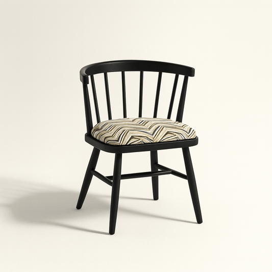 A modern black Windsor-style chair with a curved spindle backrest and four angled legs, featuring a cushioned seat upholstered in a geometric zigzag fabric with neutral tones. The chair is photographed against a light beige background with soft shadows for a clean, realistic presentation.