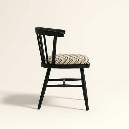 A modern black Windsor-style chair with a curved spindle backrest and four angled legs, featuring a cushioned seat upholstered in a geometric zigzag fabric with neutral tones. The chair is photographed against a light beige background with soft shadows for a clean, realistic presentation.