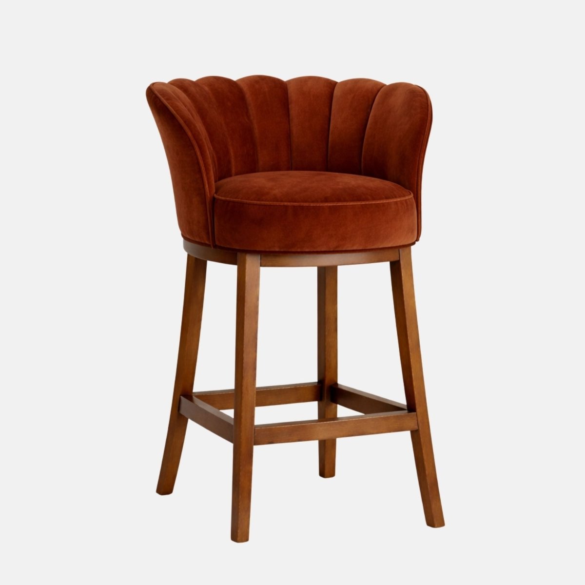 Front view of a burnt-orange velvet bar stool with a scalloped, channel-tufted wraparound back, round cushioned seat, and dark wooden legs connected by square stretcher rails, photographed on a white background.