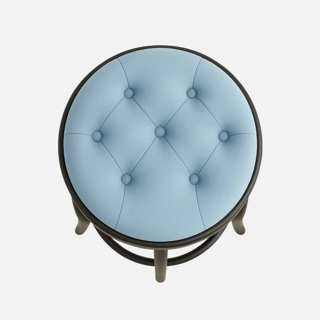 A modern round stool with a tufted light blue cushion seat, black wooden legs, and decorative curved supports with a circular footrest.