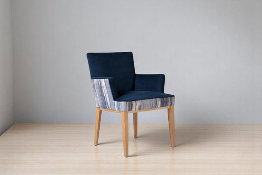 alt="Blue velvet dining chair with soft cushioned arms, contrast patterned fabric, and natural oak legs"