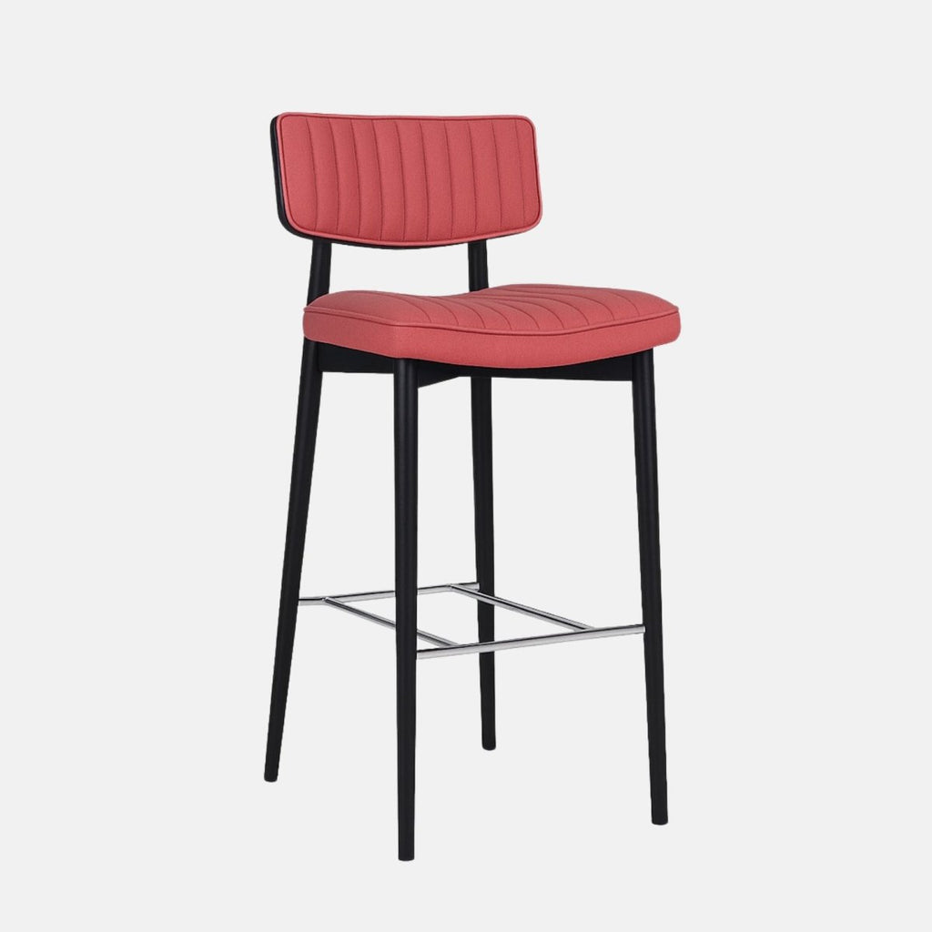 Modern bar stool with a black wooden frame, coral red upholstered seat and backrest featuring vertical channel stitching, and metal footrest.