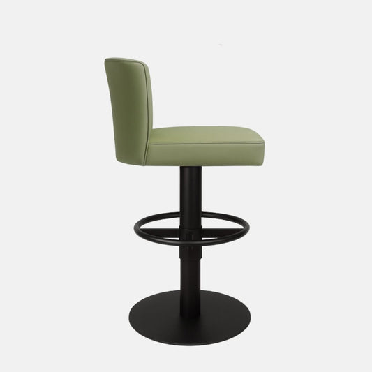 Side view of a green upholstered swivel counter stool with a low backrest, cushioned seat, black pedestal base, circular footrest ring and round base on a white background.