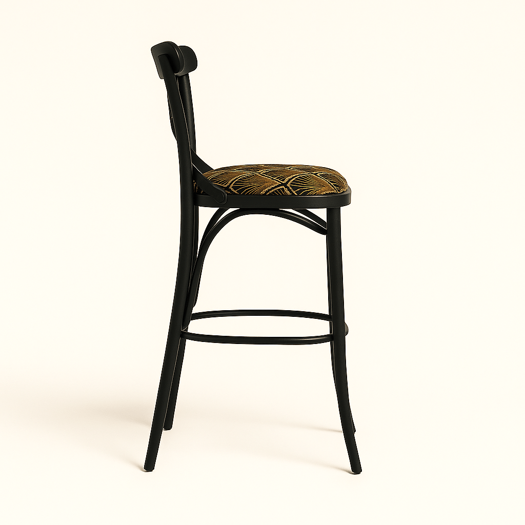 A modern black wooden barstool with an X-shaped backrest and gently curved legs, featuring a round cushioned seat upholstered in a gold and brown Art Deco patterned fabric, set against a plain beige background with a soft shadow.
