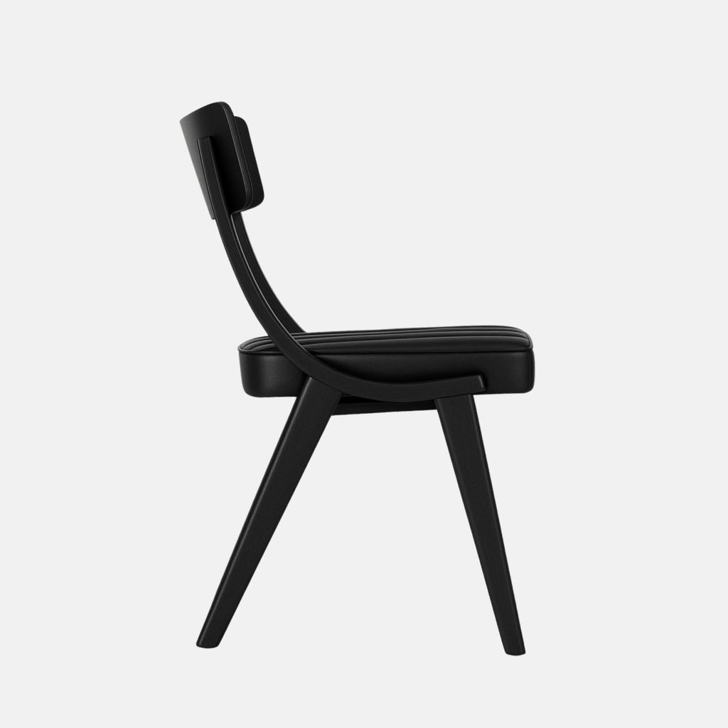 Minimalist black dining chair with a curved wooden backrest and vertically stitched black upholstered seat, supported by sleek black wooden legs, set against a light grey background
