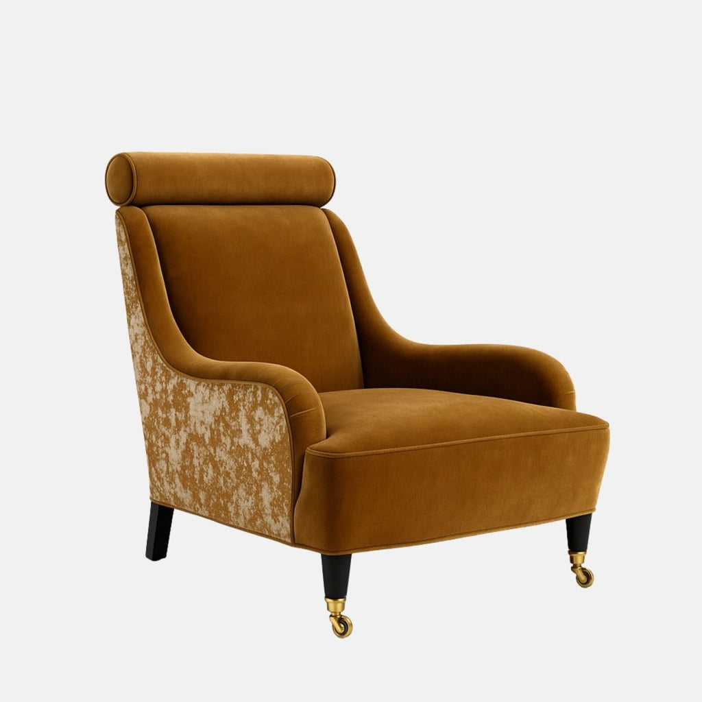 Mustard-gold velvet lounge chair with a cylindrical headrest, gently curved arms, patterned fabric on the outer sides, black legs, and brass front castors.